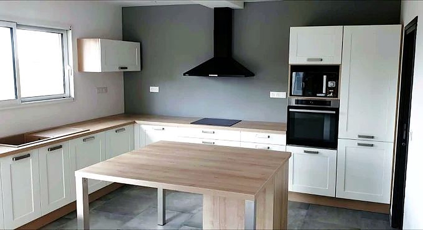 Cuisine blanche avec îlot-table et plan de travail bois
