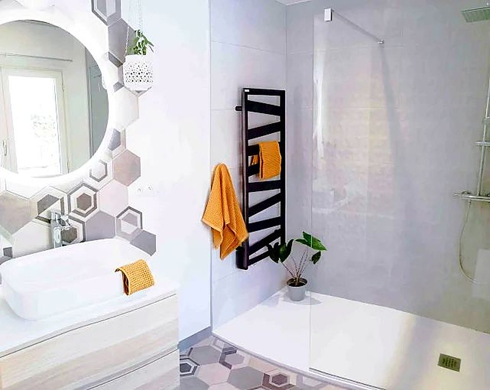Salle de bains claire avec carreaux hexagonaux et douche vitrée