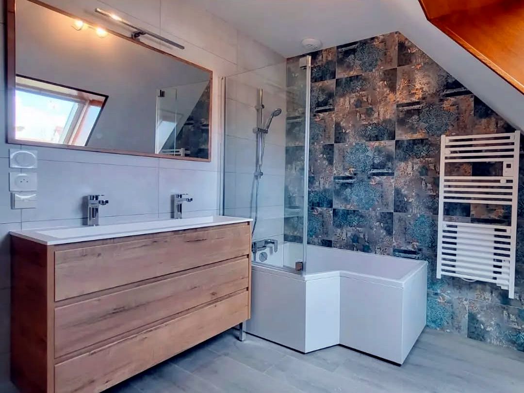 Salle de bains sous combles avec baignoire, meuble bois et carrelage patchwork